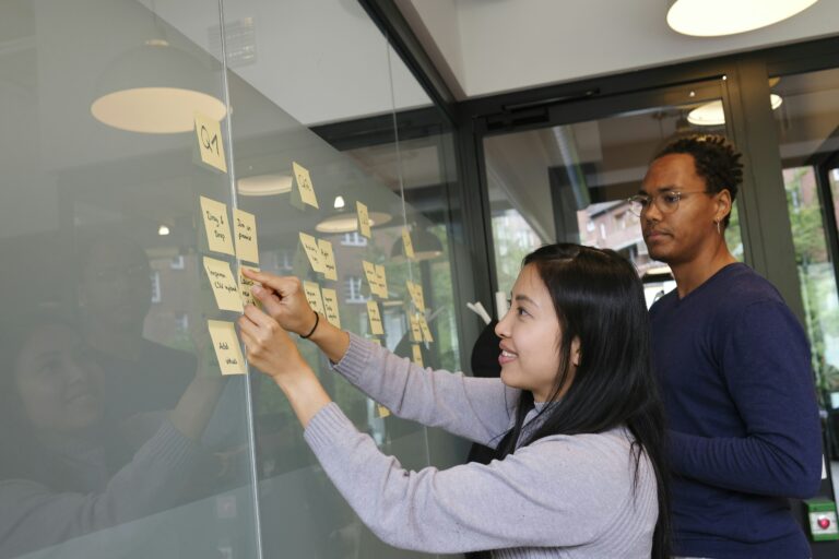 Mann und Frau kleben Post-Its an eine Wand